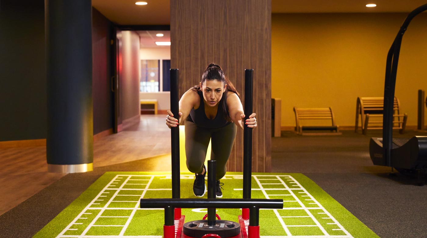 Image of woman pushing sled in the gym