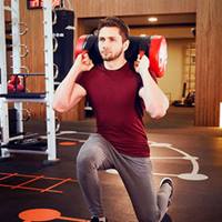 Man lunging with weighted bag in the gym